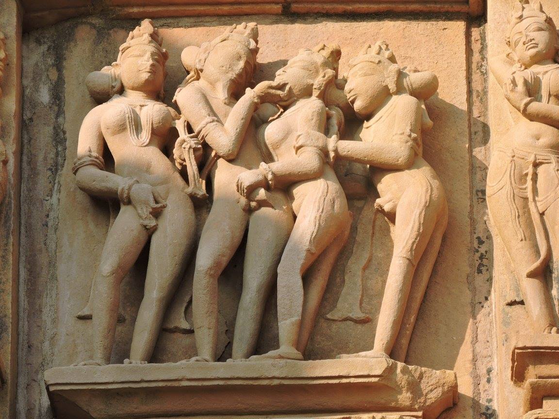 Statue of group love making in Khajuraho in where a couple fondling each other and a woman hiding her private part